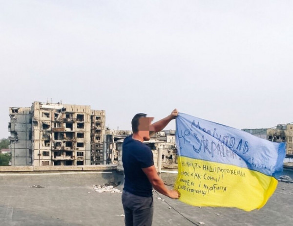 В окупованому Маріуполі розгорнули прапор України на фоні зруйнованих будинків