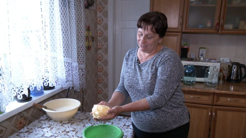 На Волині жінка збиває масло у дерев’яній маслобійці, як колись бабуся